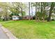 A nice view of the front exterior of the home showing yard, partial driveway, and tree coverage at 1400 Fern Forest Dr, Gastonia, NC 28054