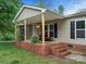 This home has a charming covered front porch with brick steps and mature landscaping at 141 Hickory Creek Dr, Gastonia, NC 28052