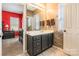 Bathroom with dark cabinets, a large mirror, and view of the bedroom at 16431 Leavitt Ln, Davidson, NC 28036