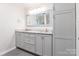 Bathroom with gray cabinets, double sinks, a large mirror, and gray tiled floor at 1720 Gaither Rd, Belmont, NC 28012