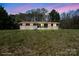 Single-story home shows exterior at dusk with a large front lawn, highlighted windows, and mature trees at 174 Maske Rd, Mount Gilead, NC 27306