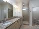 A well-lit bathroom featuring double sinks with granite countertops, a large mirror, and a glass shower at 314 Flat Rock Dr, Denver, NC 28037