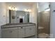 Bathroom featuring double sinks, granite countertops, a large mirror, and a glass-enclosed shower at 314 Flat Rock Dr, Denver, NC 28037