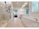 Bright bathroom with a soaking tub, glass shower, and large mirror at 320 Falesco Ln, Matthews, NC 28105