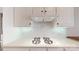 Close up of a modern gas range with white cabinets, a tile backsplash, and under-cabinet lighting at 320 Falesco Ln, Matthews, NC 28105