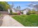 Lovely exterior with a long driveway, white brick, mature landscaping, and a grassy yard at 4541 Bradbury Dr, Charlotte, NC 28209