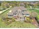 An aerial view showcases a brick home with a deck, outdoor kitchen, stone patio, landscaping, and verdant lawn at 516 White Tail Ter, Waxhaw, NC 28173