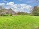 A lush green backyard with an expansive lawn and mature landscaping surround the rear of the beautiful brick home at 516 White Tail Ter, Waxhaw, NC 28173