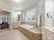 Bright bathroom boasts a tiled soaking tub and separate vanities with tiled floors and ample natural light at 516 White Tail Ter, Waxhaw, NC 28173