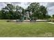 Community playground with slides, climbing structures, and benches surrounded by lush green grass and mature trees at 533 Cedar Knoll Cir, Pineville, NC 28134