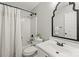 Bright bathroom featuring a white vanity, toilet, and shower with dark accents and a framed mirror at 5549 Lemley Nw Rd, Concord, NC 28027
