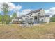 Backyard view of a modern white house with a pool, bar area, covered porch, fire pit, and lush landscaping at 6006 Waxhaw Crossing Dr, Waxhaw, NC 28173