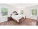 Main bedroom with wood-look floors, decorative pillows, and bright natural light from the windows at 6006 Waxhaw Crossing Dr, Waxhaw, NC 28173