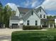 Elegant two-story home with a gray roof, white siding, and attached garage surrounded by greenery at 6006 Waxhaw Crossing Dr, Waxhaw, NC 28173