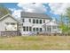 Backyard view of a modern white house with a pool, bar area, covered porch, and lush landscaping at 6006 Waxhaw Crossing Dr, Waxhaw, NC 28173