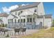 Backyard view of a modern white house with a pool, covered porch, outdoor seating, and lush landscaping at 6006 Waxhaw Crossing Dr, Waxhaw, NC 28173