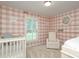 Charming Bedroom featuring pink plaid wallpaper, a white crib, and plantation shutters at 6036 Sharon Acres Rd, Charlotte, NC 28210