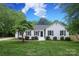 Charming white brick home with a manicured front yard, mature trees, and black shutters at 6036 Sharon Acres Rd, Charlotte, NC 28210