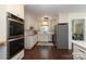 Gourmet kitchen with stainless steel appliances, white cabinets, and hardwood floors with an adjacent laundry room at 6036 Sharon Acres Rd, Charlotte, NC 28210