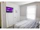 Cozy bedroom featuring a TV, window, and comfortable bed with grey striped bedding at 6124 Old Plank Rd, Charlotte, NC 28216