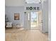 Bright foyer with hardwood floors, an open doorway, and a decorative 