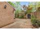 Brick-paved backyard featuring a wood gate, beautiful flowers and brick walls at 6801 Dumbarton Dr, Charlotte, NC 28210