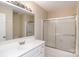 Well-lit bathroom with a white vanity, shower over tub with glass doors, and a large mirror at 6801 Dumbarton Dr, Charlotte, NC 28210