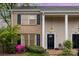 Charming two-story townhome featuring a brick facade, black shutters, and a well-maintained front yard with flowering bushes at 6801 Dumbarton Dr, Charlotte, NC 28210