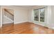 Bright living room featuring hardwood floors, neutral walls, large window, and staircase access to upper level at 6801 Dumbarton Dr, Charlotte, NC 28210
