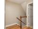 Carpeted stairway featuring light-colored walls, white spindles, and a wood handrail at 6801 Dumbarton Dr, Charlotte, NC 28210
