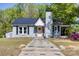 Charming one-story home with a black metal roof, brick chimney, landscaped yard, and inviting front entrance at 702 Hazel Ave, Kannapolis, NC 28083