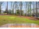 Large backyard with a deck and lawn surrounded by a black fence and trees with other houses in the background at 7186 Barleywood Dr, Locust, NC 28097