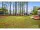 Grassy backyard with a trampoline and deck with a fence line and tall trees at 7186 Barleywood Dr, Locust, NC 28097