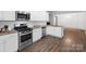 Modern kitchen features white cabinets, stainless steel appliances, granite countertops, and hardwood floors at 7186 Barleywood Dr, Locust, NC 28097