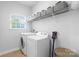 Bright laundry room with shelving, storage, a washing machine, a dryer, and a cleaning tool at 7186 Barleywood Dr, Locust, NC 28097