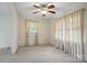 Bright bedroom with a ceiling fan and natural light streaming through the windows and neutral curtains at 819 Old Dutch W Rd, Indian Trail, NC 28079