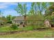 Picturesque backyard featuring a brick patio, pergola, mature trees, and charming red shed at 8605 Ducksbill Dr, Charlotte, NC 28277
