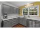 Well-lit kitchen with stainless steel dishwasher, gray cabinets and garden view at 8605 Ducksbill Dr, Charlotte, NC 28277