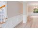 Hallway featuring wood floors and decorative wainscoting leading to a living area with a window and chandelier at 1000 Potters Bluff Rd, Monroe, NC 28110