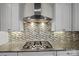 Cooktop and range hood are set against a mosaic backsplash in this sleek kitchen at 1012 Harper Lee Dr, Newton, NC 28658