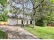 Inviting cream colored home with an attached garage and mature trees in the front lawn at 10432 Camelback Cir, Charlotte, NC 28226