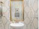 Stylish powder room featuring a pedestal sink, gold mirror, and unique wallpaper at 11234 Smokethorn Nw Dr, Concord, NC 28027