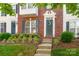 Up-close townhome door with brick facade, green shutters, flower beds, and healthy shrubbery at 12036 Duke Lancaster Dr, Charlotte, NC 28277