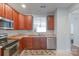 Bright kitchen with stainless steel appliances, wooden cabinets, and a sink overlooking the living room at 12036 Duke Lancaster Dr, Charlotte, NC 28277