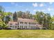 Charming home with a red roof, white exterior, and grand columns set against a backdrop of mature trees and greenery at 1233 General Hoke Dr, Lincolnton, NC 28092