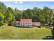 An impressive home with red roof and white facade surrounded by lush greenery and a vast, well-manicured lawn at 1233 General Hoke Dr, Lincolnton, NC 28092