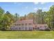 A striking home with a red roof, white exterior, and grand columns, nestled amidst mature trees and lush greenery at 1233 General Hoke Dr, Lincolnton, NC 28092