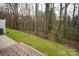 Backyard featuring a brick patio, grassy area and wooded surroundings, providing a serene outdoor retreat at 16631 Commons Creek Dr, Charlotte, NC 28277