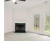 Cozy living room features a fireplace with green marble, grey carpet, and French doors with wooded view at 16631 Commons Creek Dr, Charlotte, NC 28277