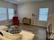 Cozy living room with two windows, a red chair, wooden floors, and tasteful decor at 1843 Old Rivers Rd # 209, Concord, NC 28027
